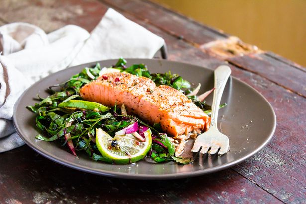 Salmon dish with salad on a black plate with a fork