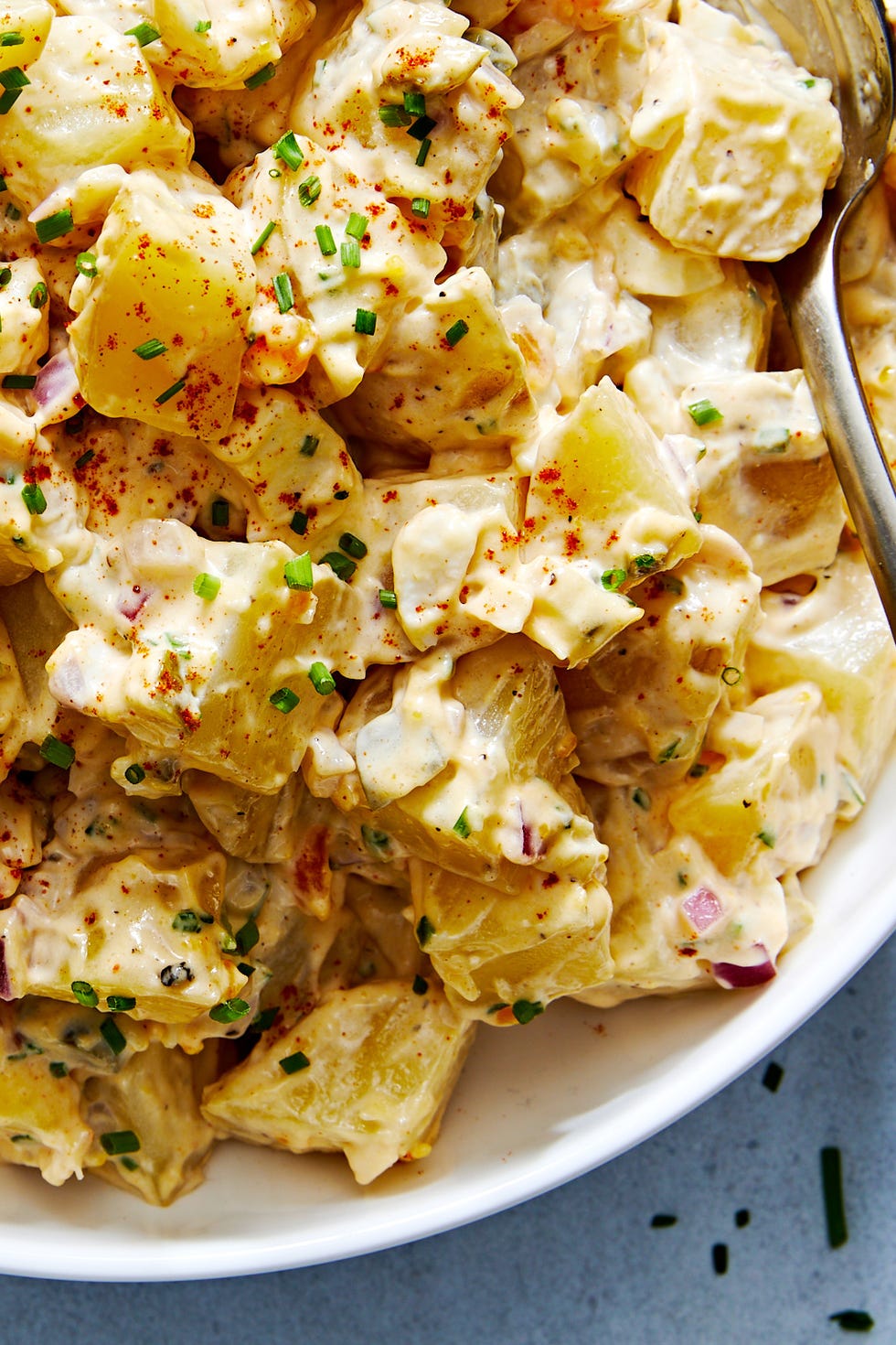 classic potato salad with pickles, onions, and topped with paprika and chives
