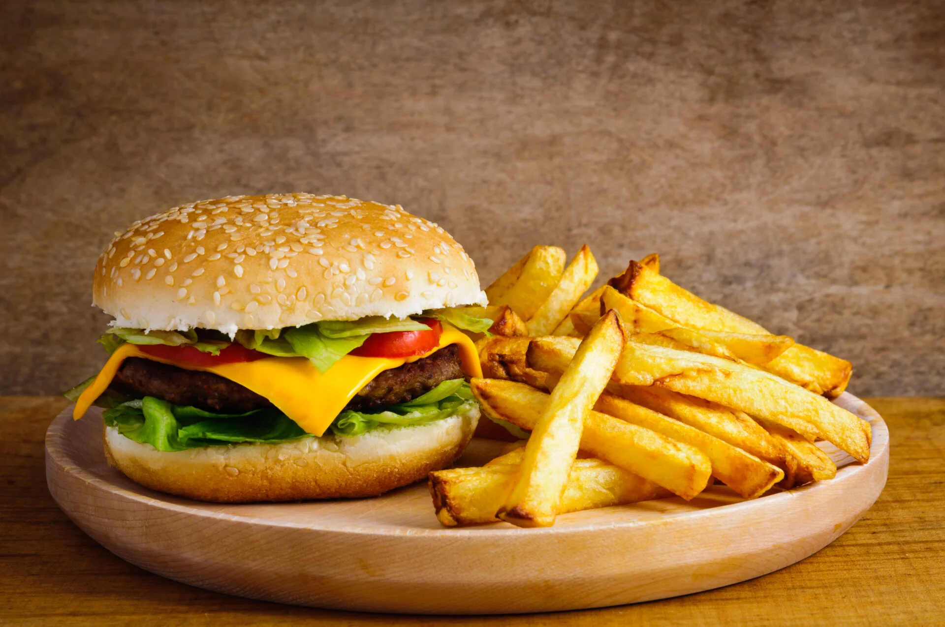 Fast food hamburger and french fries on a wooden plate