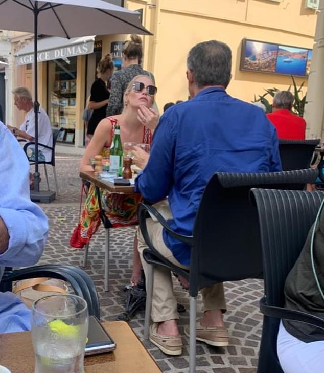 The 30-year-old model wore a vibrant multi-coloured sundress teamed with a pair of oversized tortoiseshell sunglasses paired with a red leather clutch bag draped over her shoulder