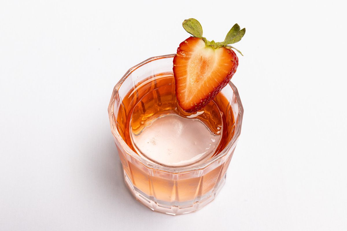 A red drink with a strawberry garnish.