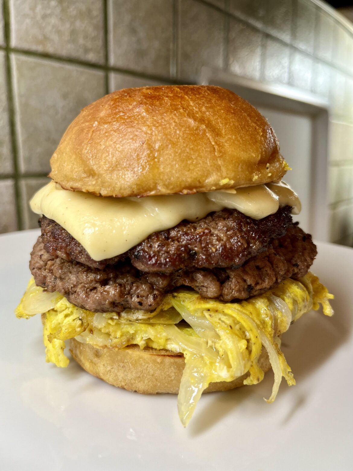 A sourdough double cheeseburger with scrambled eggs, grilled onions, cracked pepper, gouda and mustard | THE FAT CHAMOIS