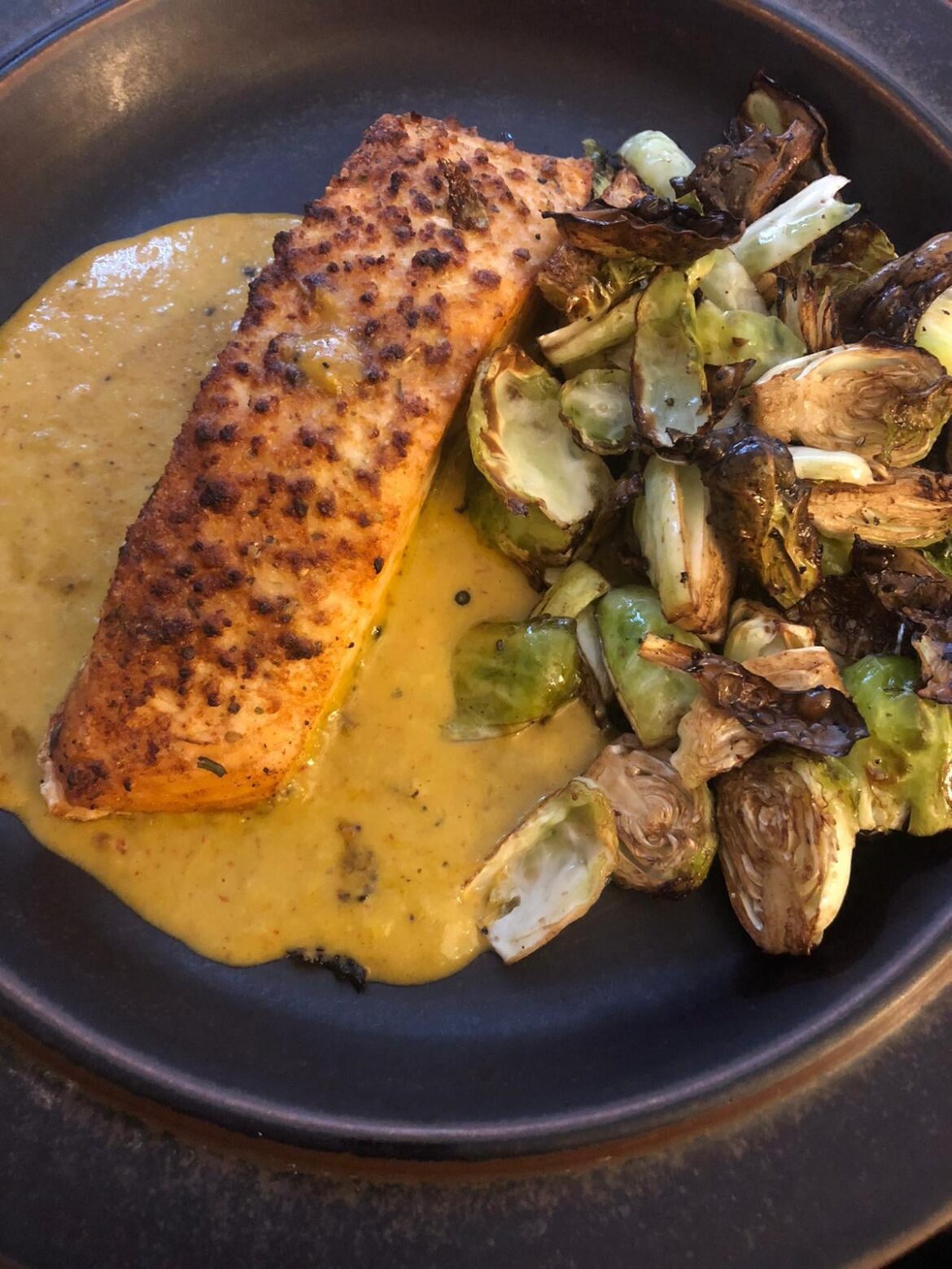 Salmon on top off Lime Jalapeño and Sriracha sauce with Brussel sprouts on the side