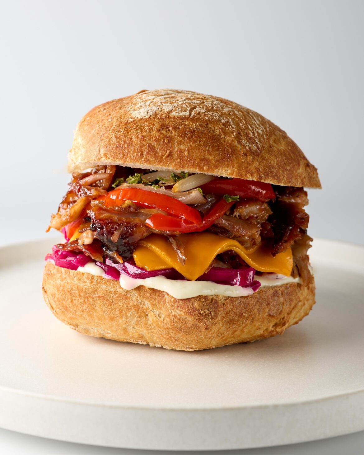 Slow-cooked BBQ pork with jalapeño mayo, pickled red cabbage, roasted peppers & shallots, melted cheddar and dried jalapeño flakes.