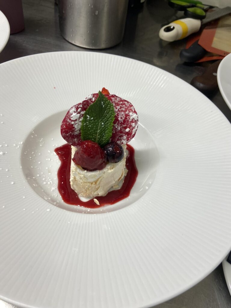 Summer berry and lemon pavlova, crystallised rose petals and raspberry coulis