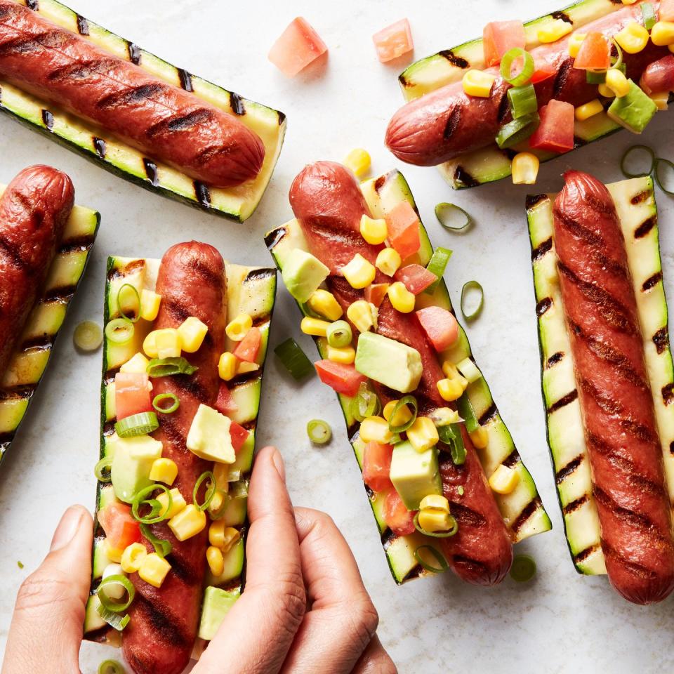 grilled hot dogs in between grilled zucchini topped with avocado salsa