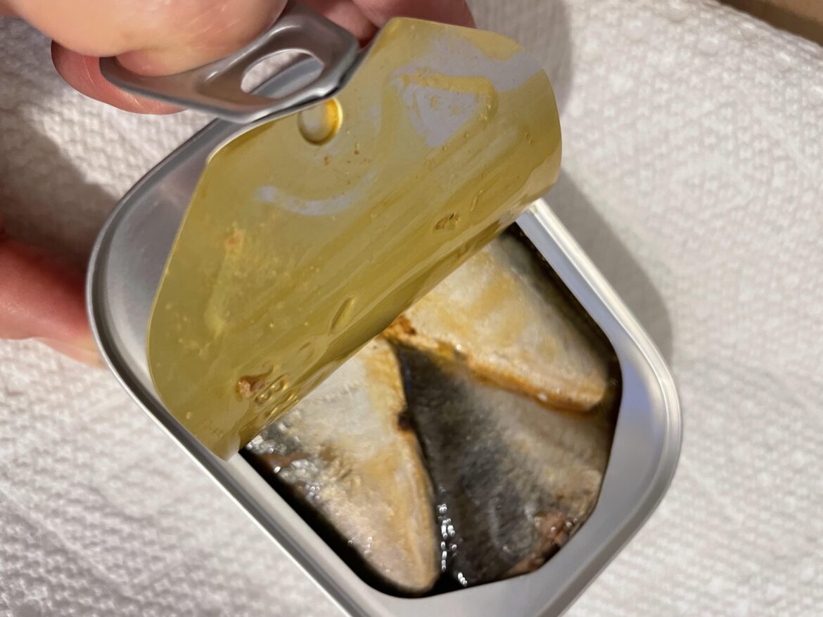 We need a word for the specific anxiety you feel when peeling back the lid, hoping you don’t get flicked with fishy oil
