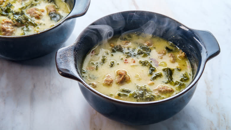 Black crocks of creamy soup with meat and greens