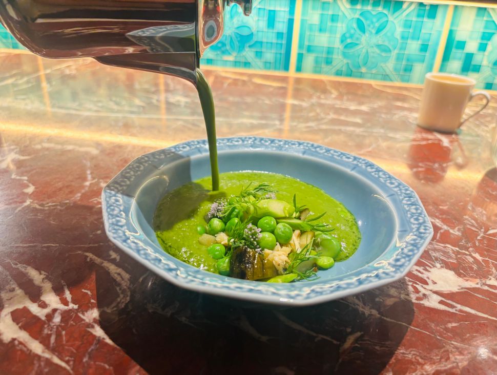 A vibrant green asparagus soup is poured tableside into a bowl of crab, peas, and herbs at Maison Passerelle.