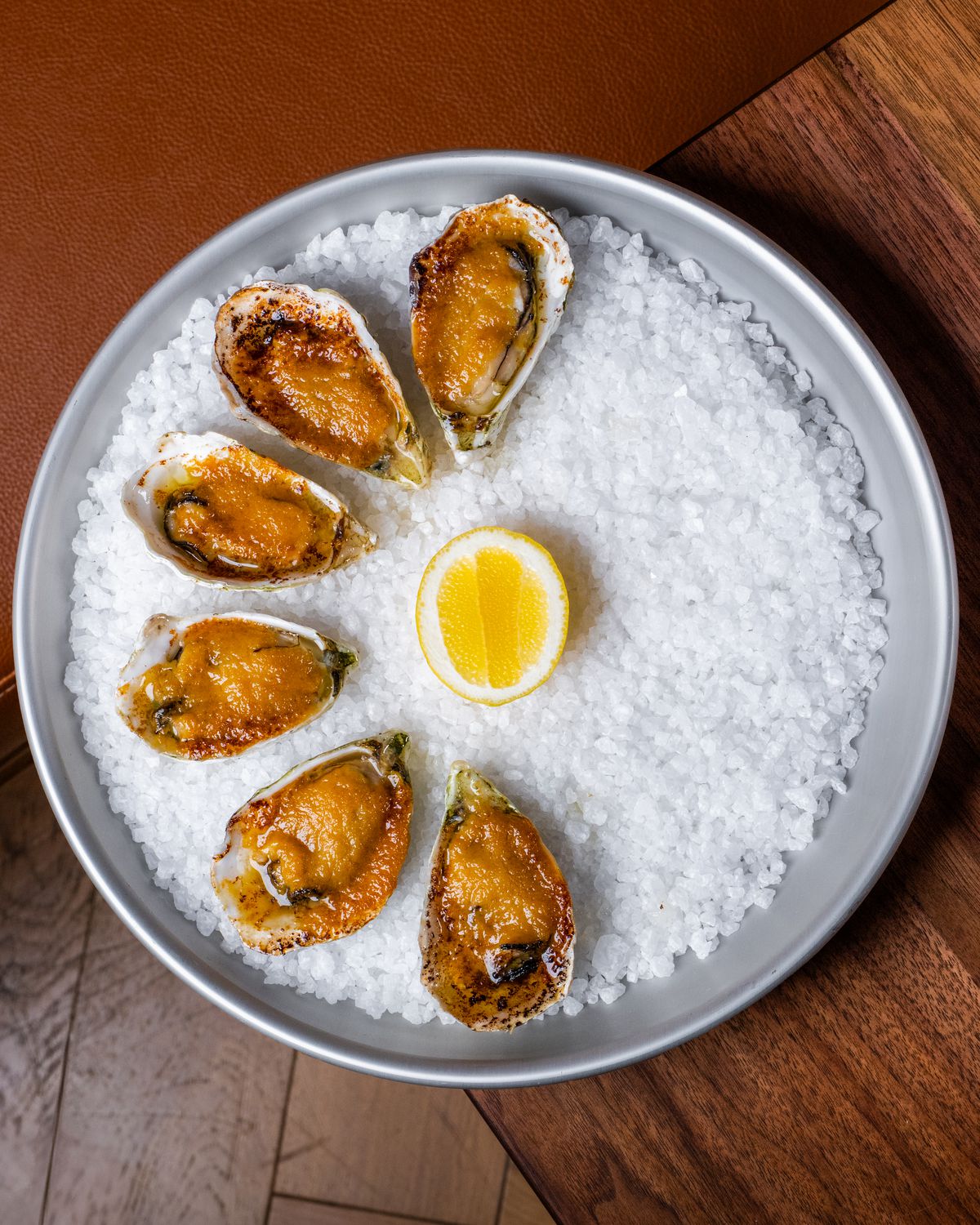 Six grilled oysters and a lemon slice over a bed of rock salt from Bistro Lagniappe in Healdsburg, California.