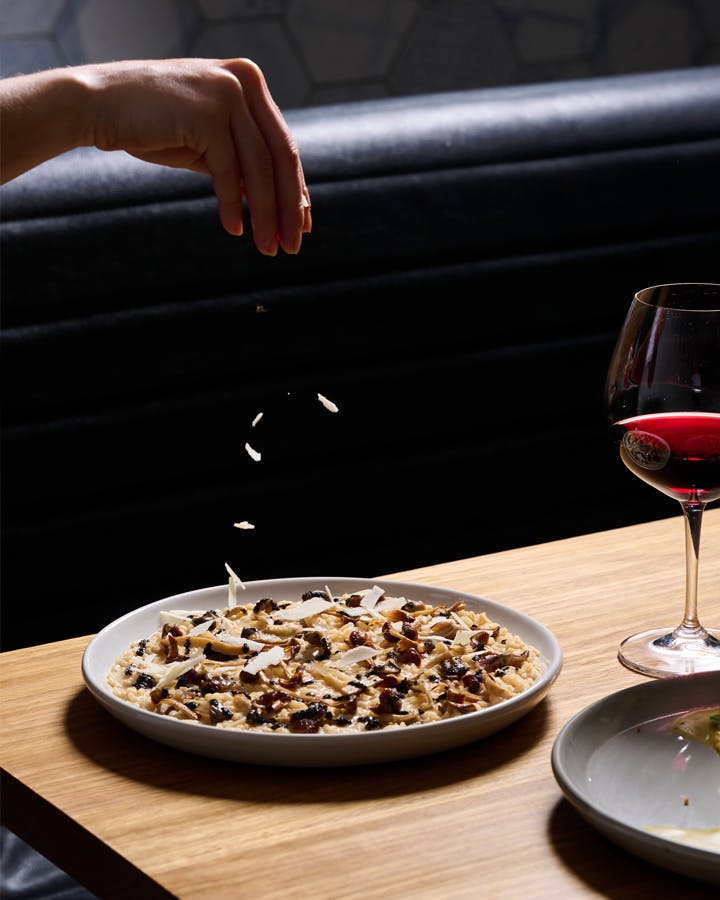 A person dropping shavings of cheese onto risotto at a best italian restaurants Melbourne CBD. 