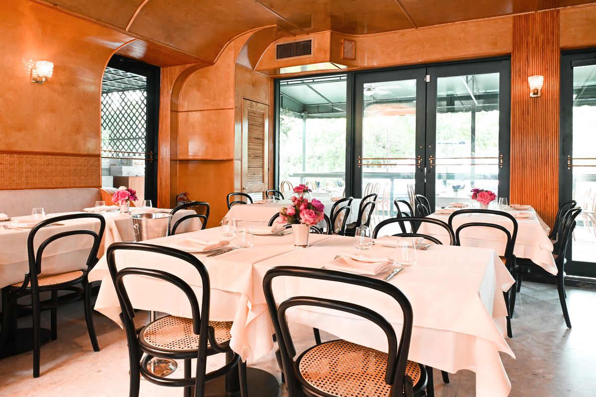The dining room at San Lorenzo with white tablecloth tables and large windows.
