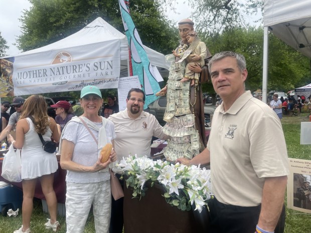 As she holds up her Italian roll, Joanne Zuppo, of Glenolden, owner of Salon 625 in Ridley Park, talks with members of The St. Anthony DiPadova Society, Frank Dattilo, center, of East Norriton, and Ted Dezzi of Mullica Hill, N.J. during last year's Italian American Heritage Festival at Rose Tree Park. The St. Anthony DiPadova Society of Southwest Philadelphia has been at the festival in Delaware County since its inception 15 years ago and will be back again this year. (PEG DEGRASSA/ DAILY TIMES)