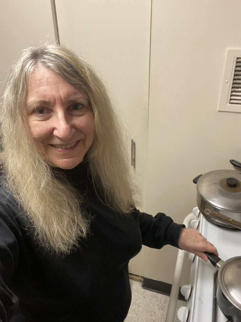 A woman with blonde hair cooking at a stovetop. 