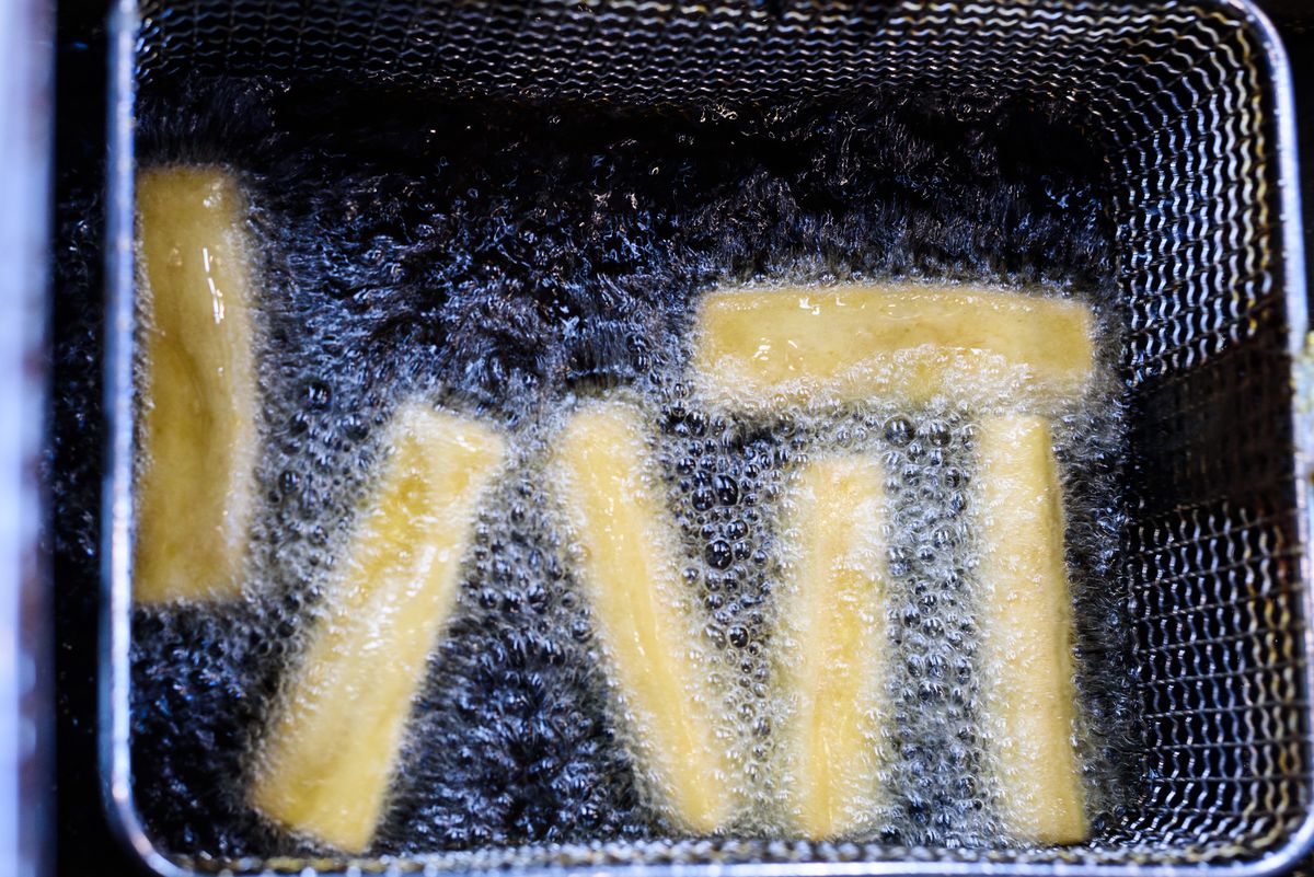 Sticks of panisse frying in a vat of oil.