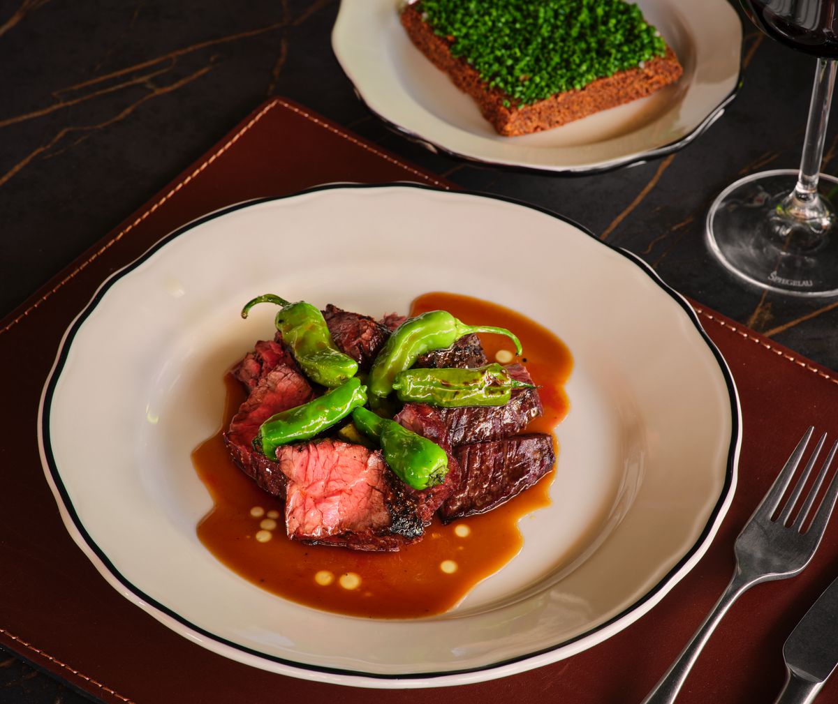 A plate of steak topped with shishito peppers at Le Calamar.