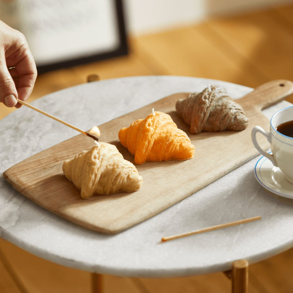 Three croissant-shaped candles on a wooden board.
