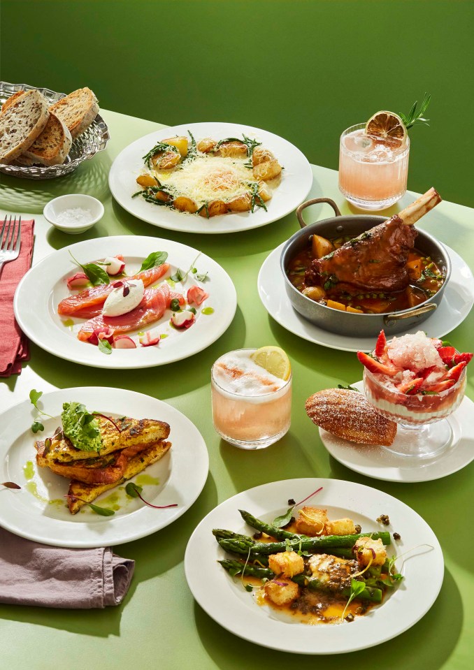 A table setting with various dishes, including lamb shank, salmon, and asparagus.