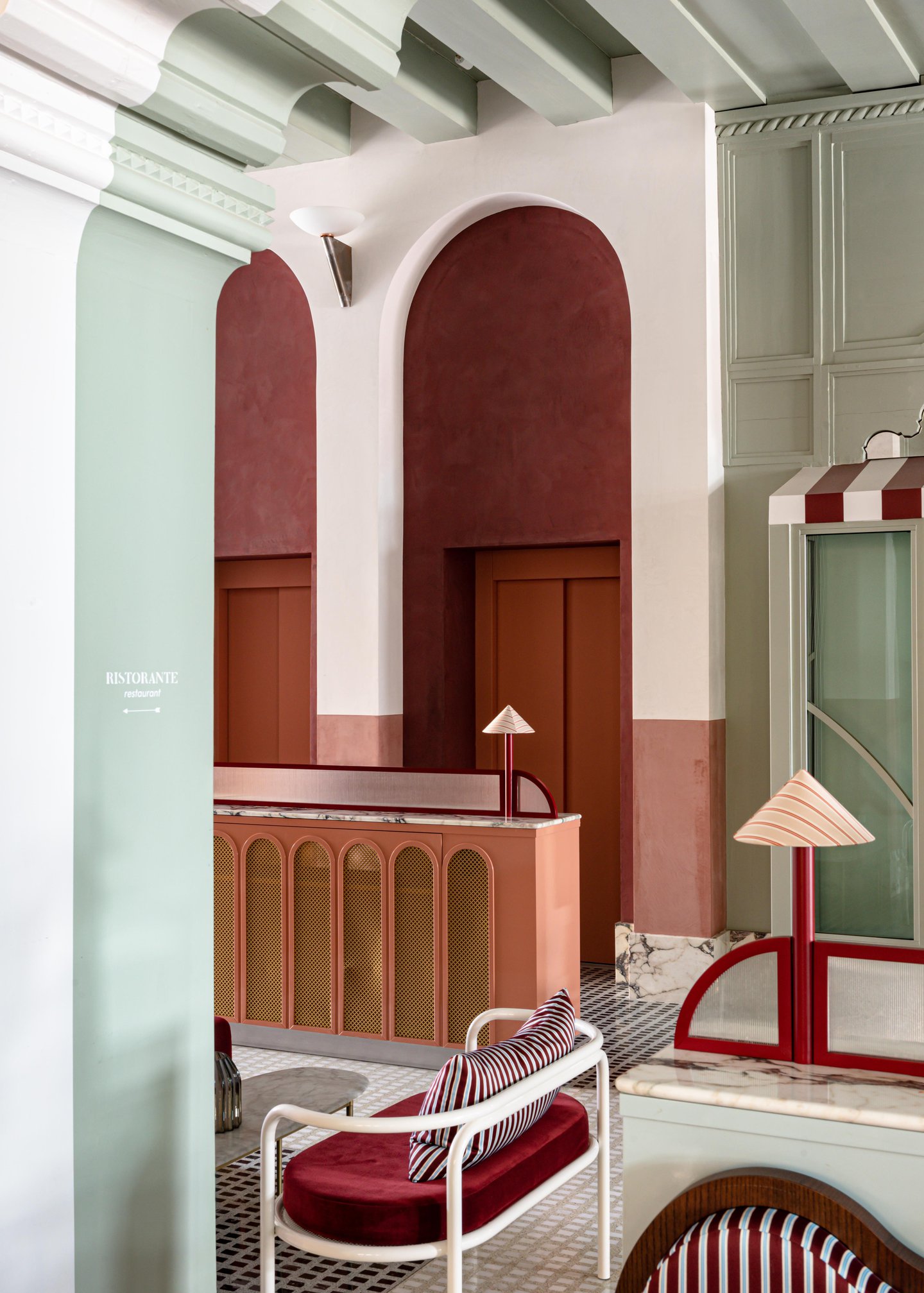 A pastel-hued restaurant with lots of arches and patterns boasts a playful aesthetic sculpted from plush velvety fabrics, glass, marbles, and plaster.