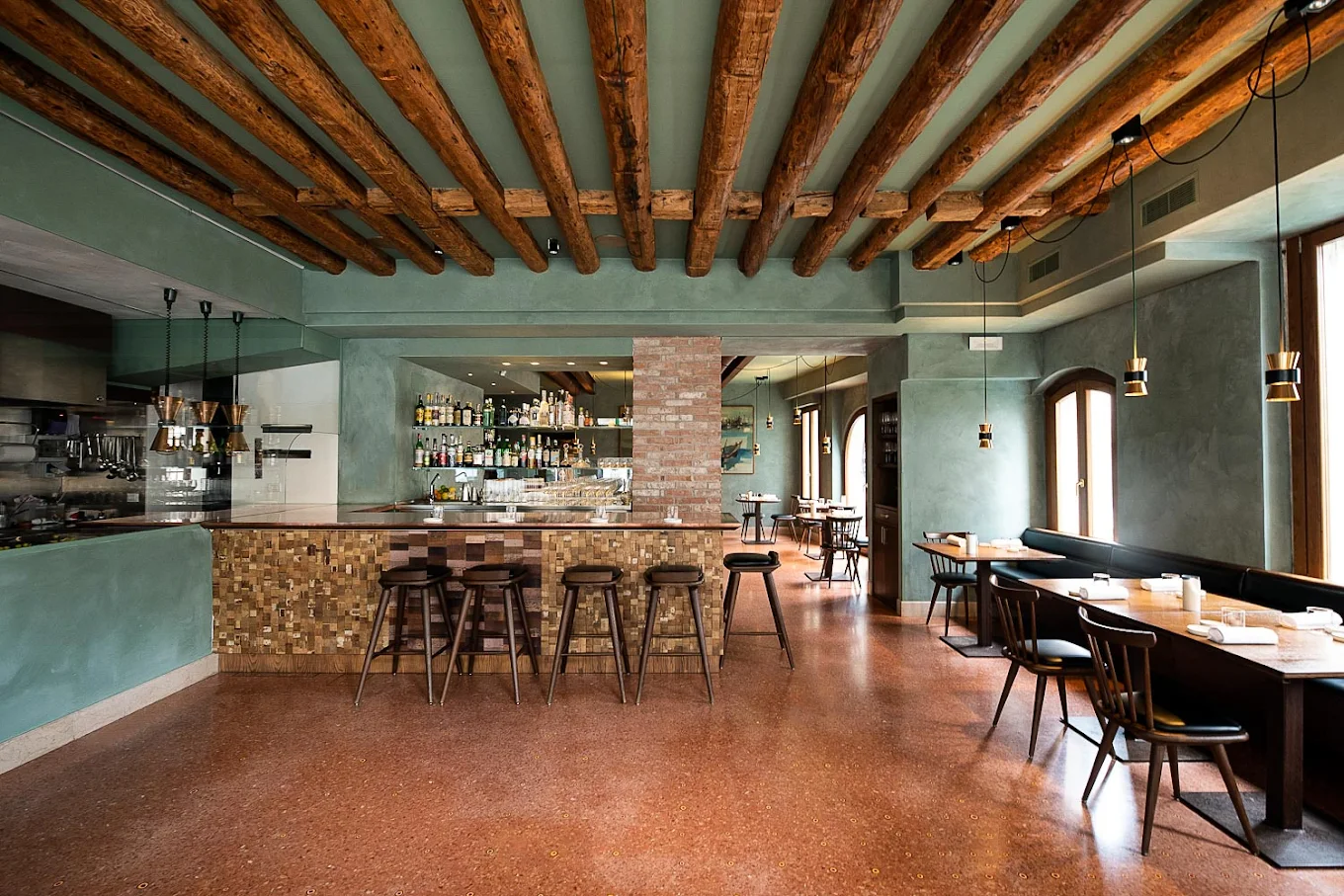 A cosmopolitan restaurant features a seagreen palette made even more vibrant by terracotta floors, stone touches, exposed beams, and occasional brass and chrome accents.