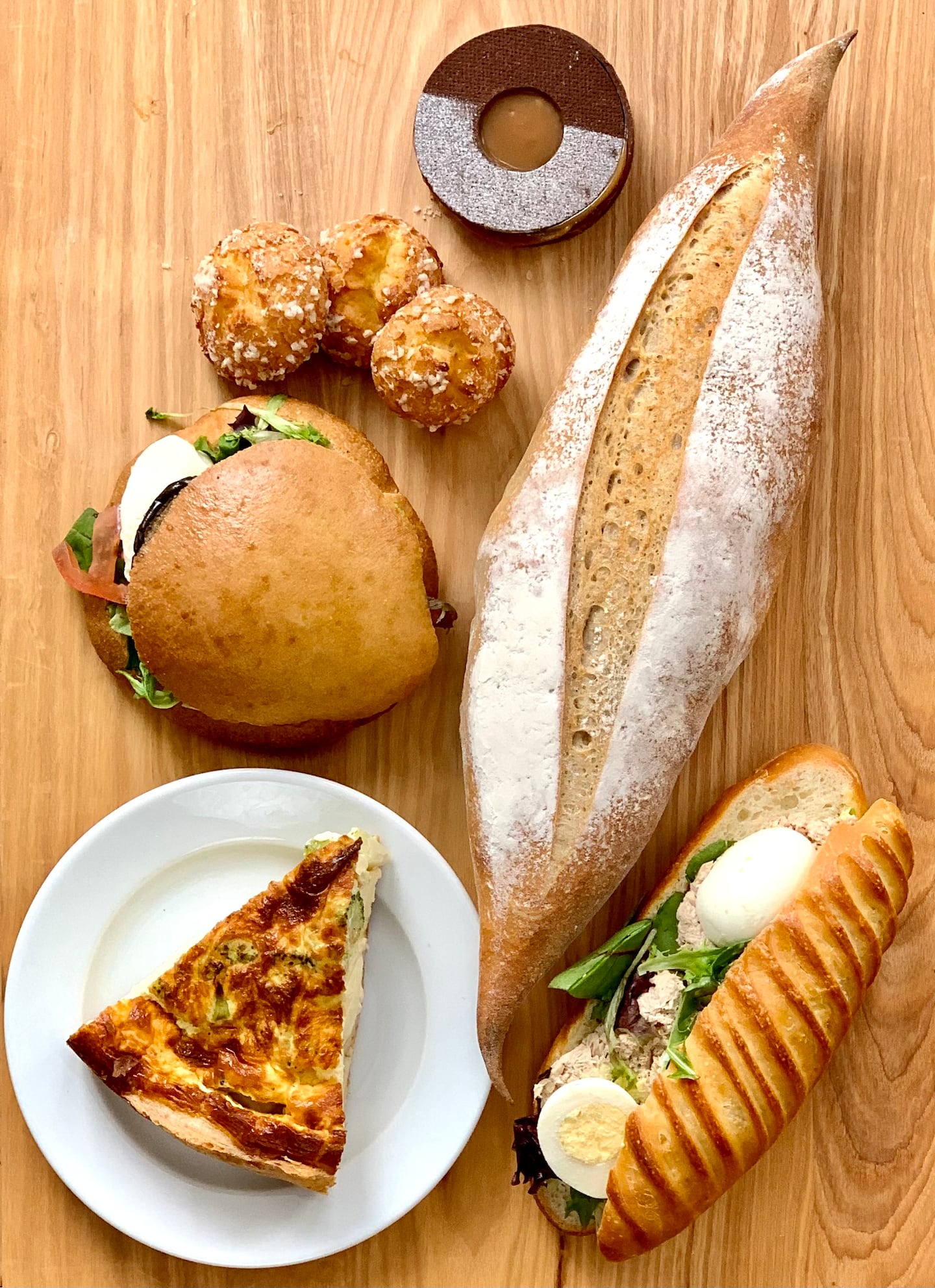 Items at Colette Bakery in Medford include (clockwise from top): tarte choco caramel, baguette de campagne, tuna sandwich, vegetable quiche, eggplant sandwich, and chouquettes.