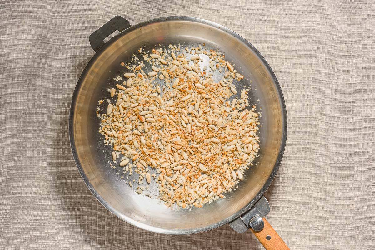 The breadcrumbs and pine nuts for the sardine pasta being toasted in a skillet.