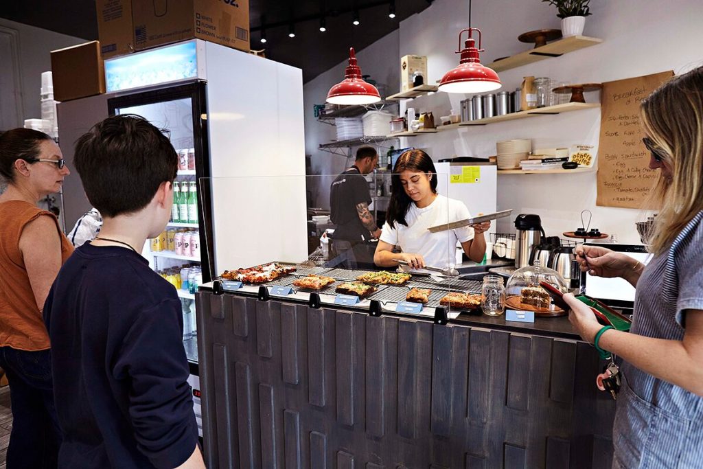 Red Hound Pizza co-owner Andrea Alvarez (center) puts out freshly made pizzas.