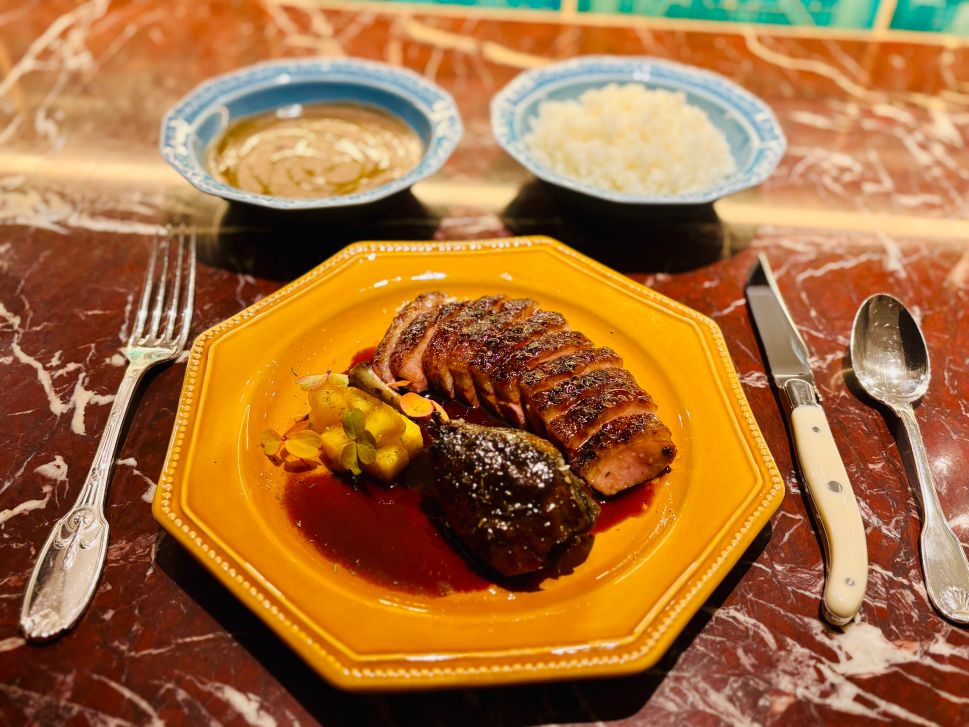 A plate of sugarcane-glazed duck breast and confit leg is served with pineapple and tamarind sauce at Maison Passerelle.