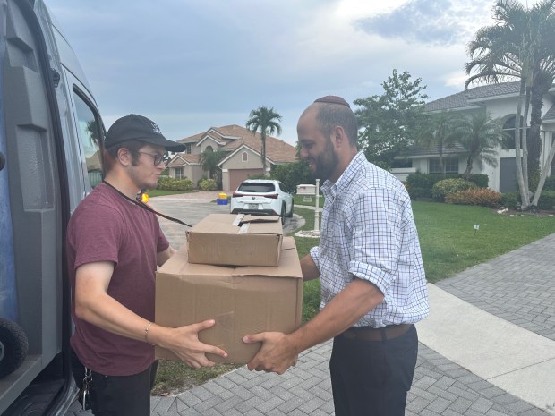 Driver Yehuda Fishman delivers food packages from the Miami Kosher Ko-Op to Avi Newman at his home in Boca Raton (Ben Feferman/courtesy).