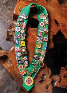 The colorful regalia of Lacey King, Naples Bailliage’s current conseiller gastronomique provincial honoraire, denoting society rank and event involvement.. Photo by Nick Shirghio