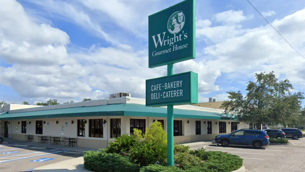 exterior of a deli with a green awning and a big green sign at the entrance