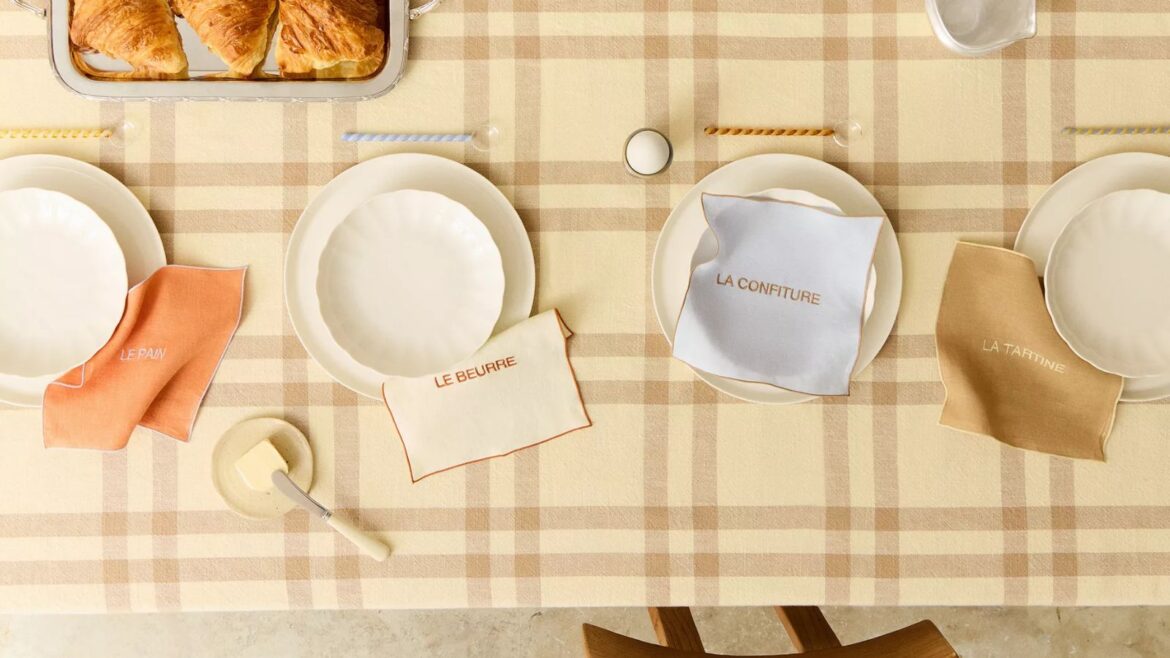 french bistro inspired tablescape by zara home with a butter yellow checked tablecloth, french pastel napkins, twisted glass spoons, and croissants