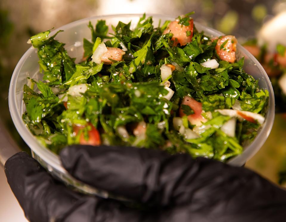 Owner Najwa Saad of Cedar & Olive Mediterranean Grill in Jacksonville Beach portions out tabouli for customers.