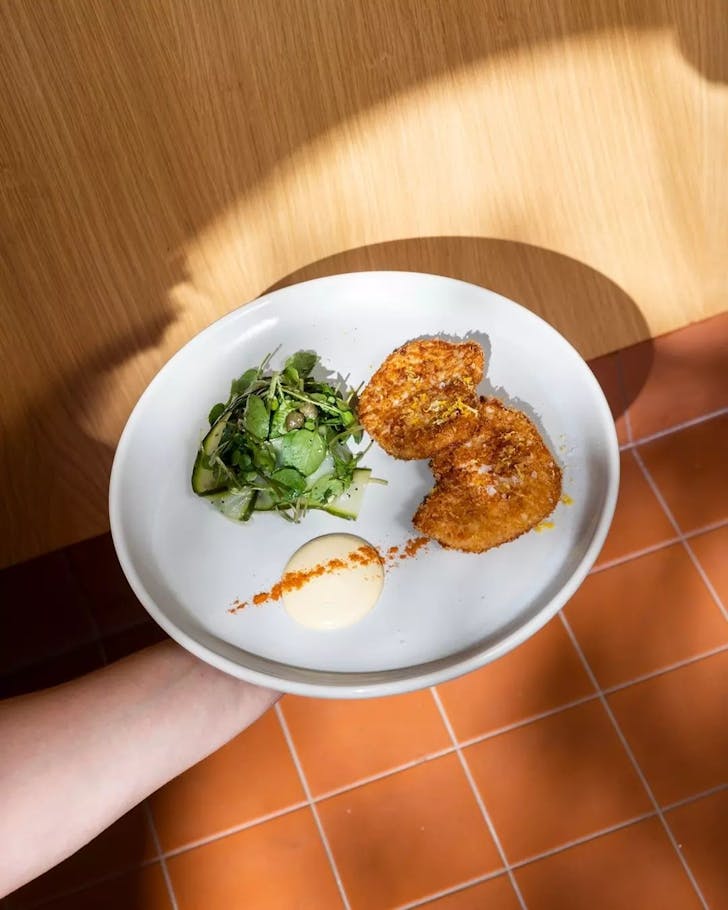 Someone holding a plate of the swordfish schnitzel from Canteen Pizza