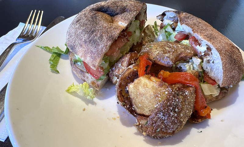 A sandwich and roasted potatoes on a plate