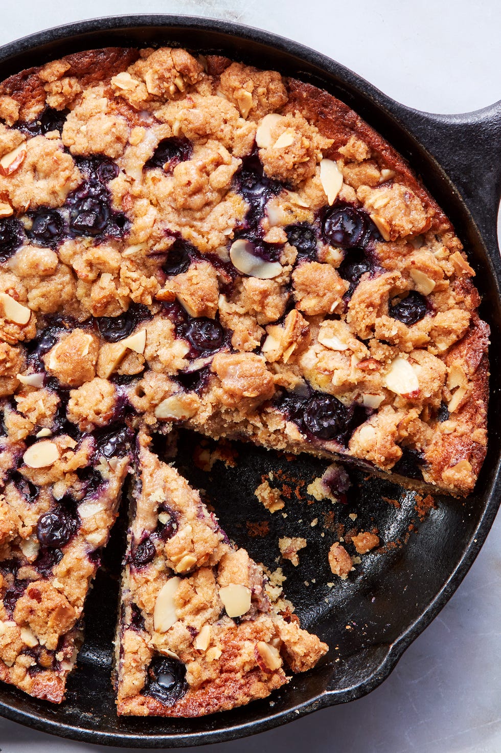 blueberry cake in a skillet topped with a crumble