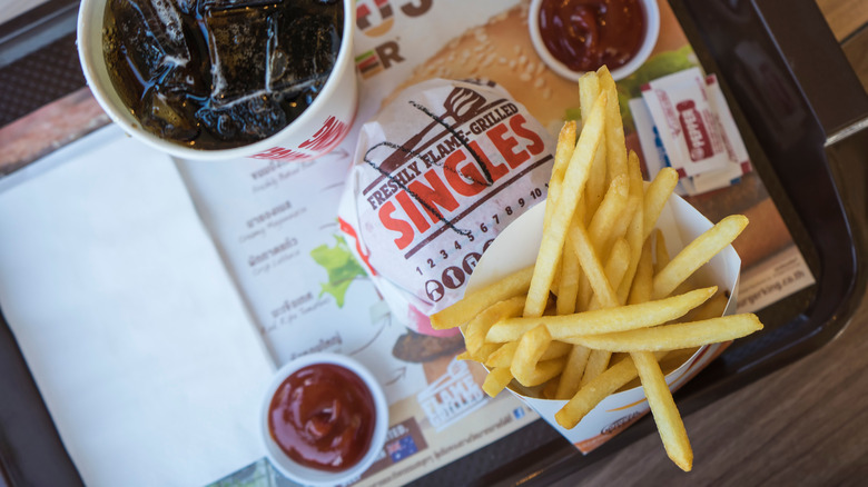 burger king fries on tray with burger, ketchup containers and soda