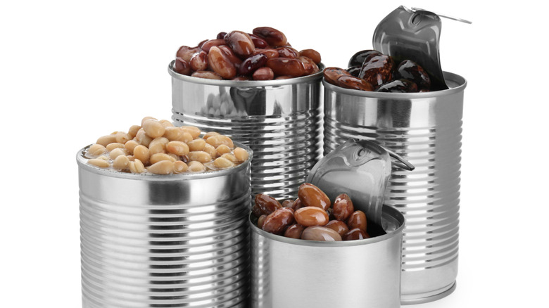 Tin cans with different kidney beans on white background