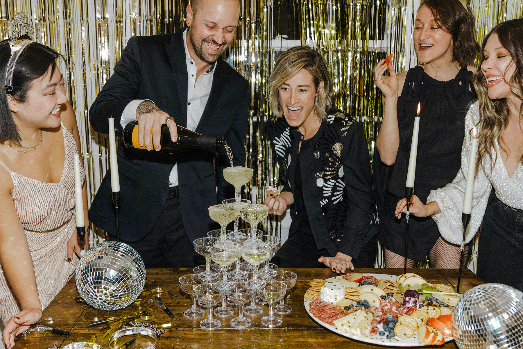 People standing around a table, pouring in a champagne tower.