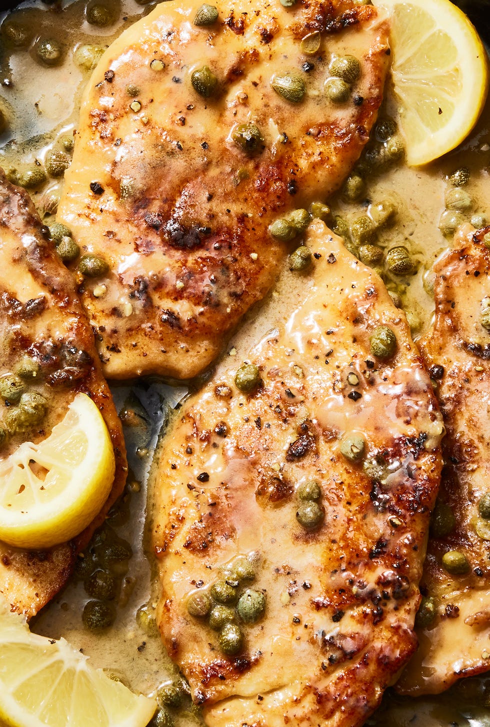 chicken piccata in a skillet with lemon butter caper sauce