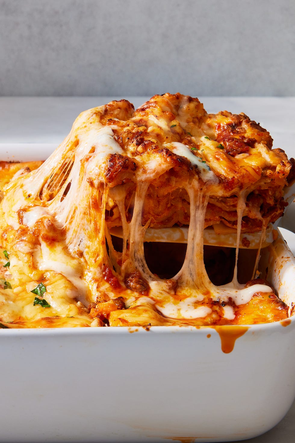 classic lasagna in a white pan topped with fresh herbs