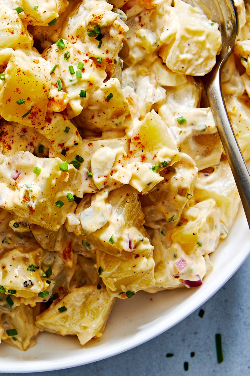 classic potato salad with pickles, onions, and topped with paprika and chives