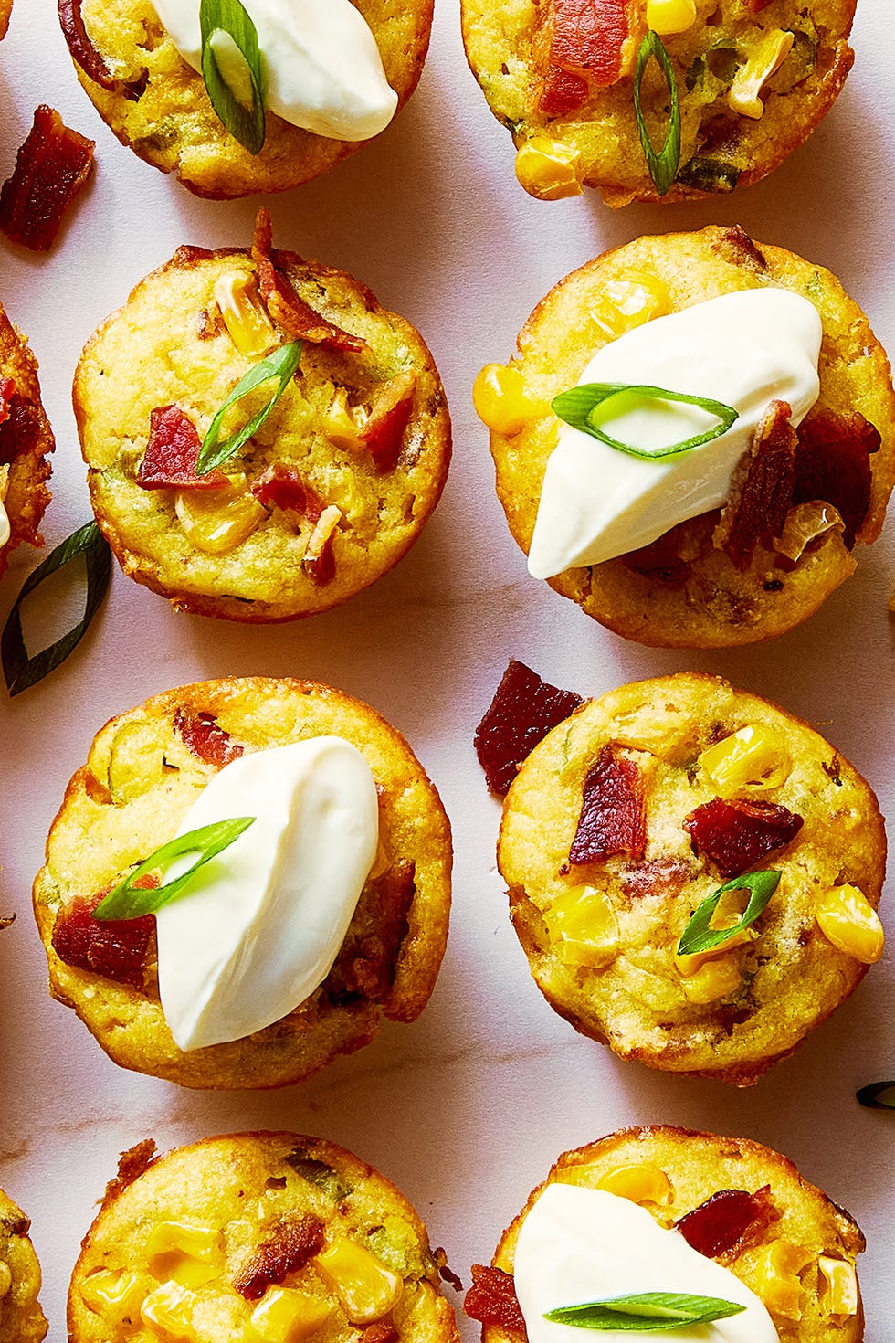 loaded cheesy corn bites topped with sour cream, sliced scallions, and bacon