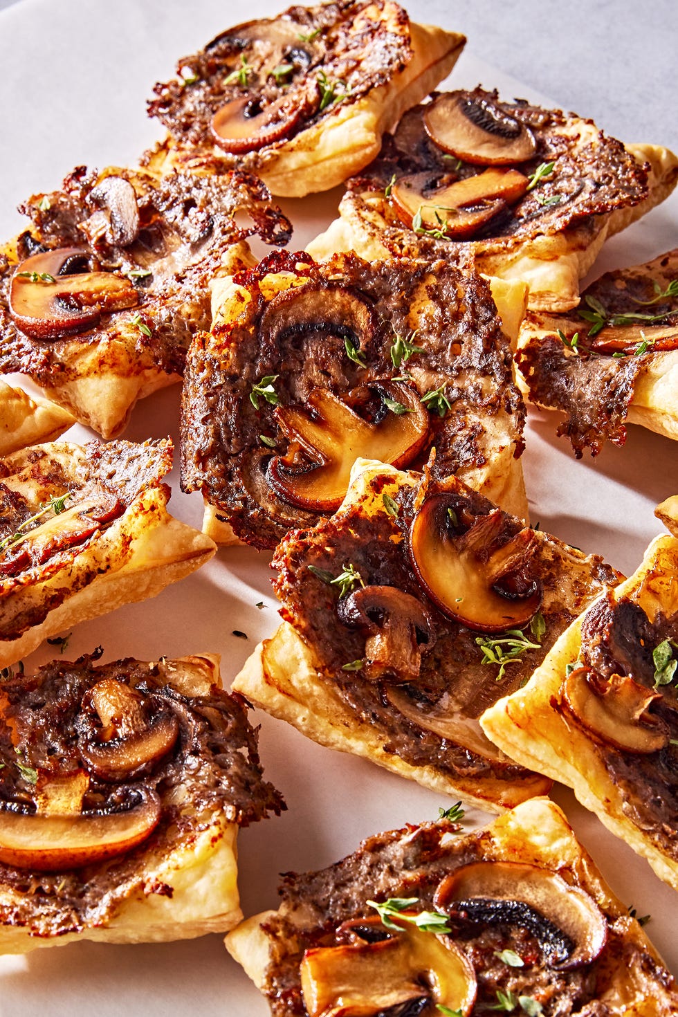 individual puff pastry squares topped with a cheesy mushroom duxelles, slices of roasted mushrooms, and fresh thyme