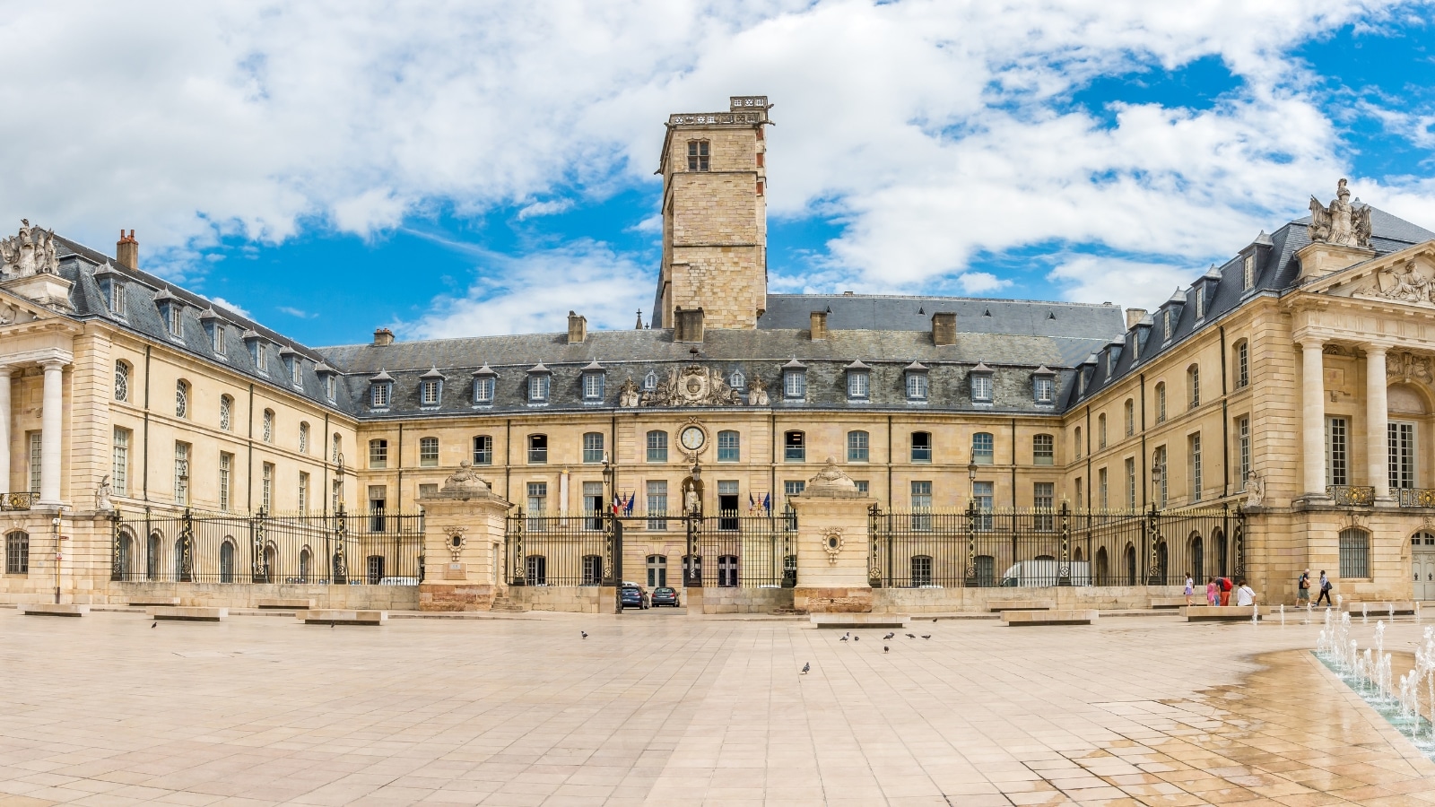  A panoramic photograph capturing the Place of Libertaion in Dijon, France. The image showcases the open square with surrounding buildings, streets, and urban elements. Noteworthy architectural features include the buildings' facades and the overall layout of the square.
