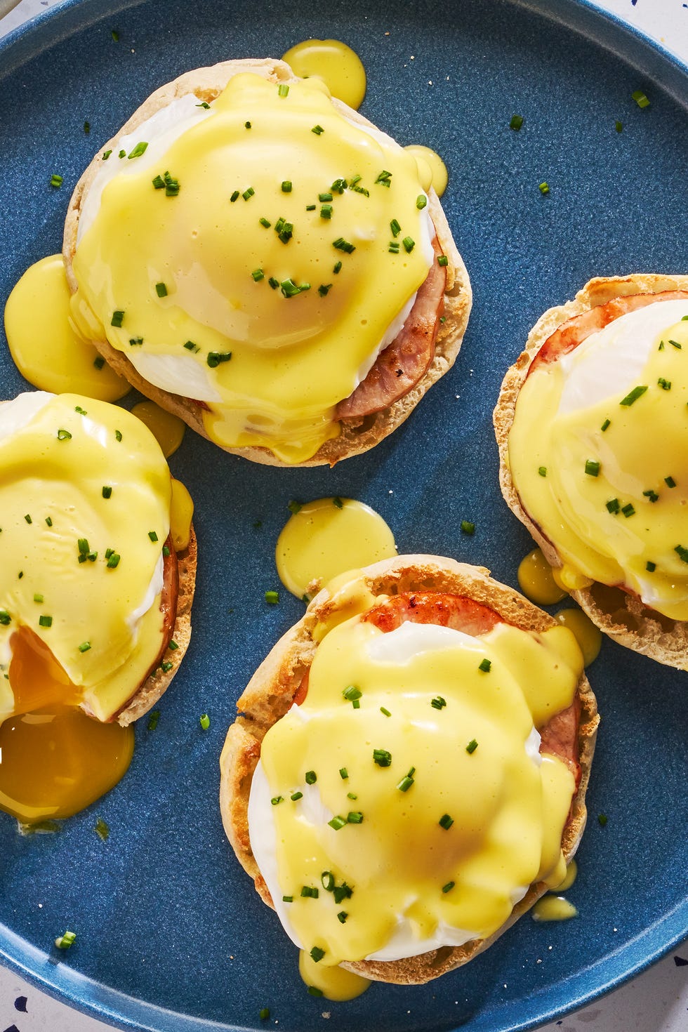 english muffins topped with ham, poached eggs and hollandaise on a plate