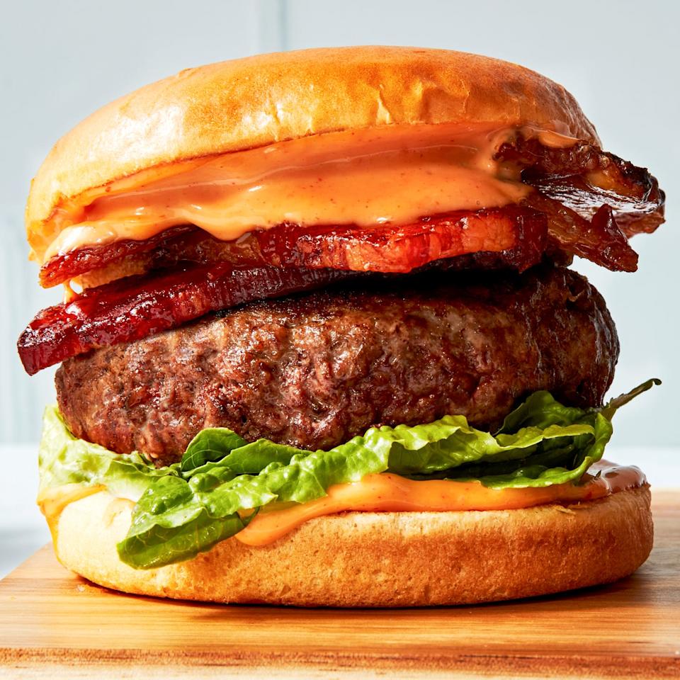 beef burger with bacon, lettuce, and a spicy sauce