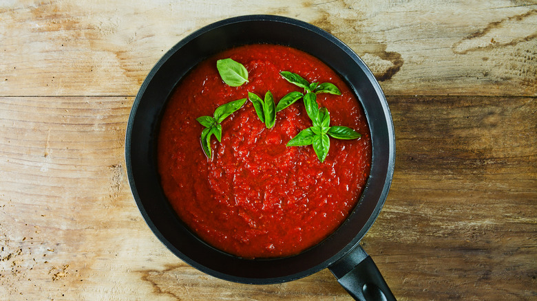 Tomato sauce in a pan with basil leaves