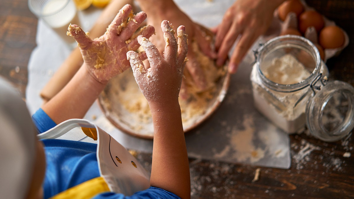 child and mother making a cake together