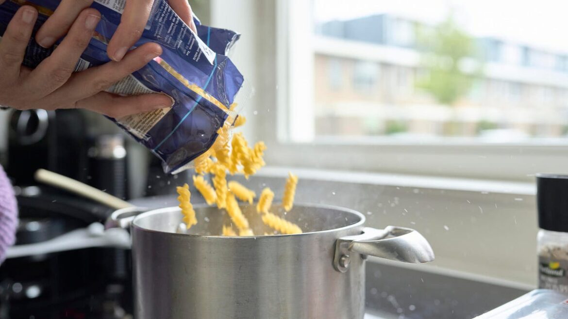 person pouring pasta into pot